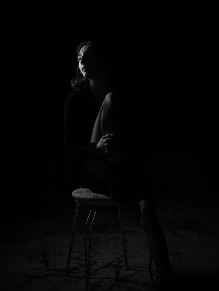 about-02 Dramatic black and white portrait of a woman seated, evoking emotions.