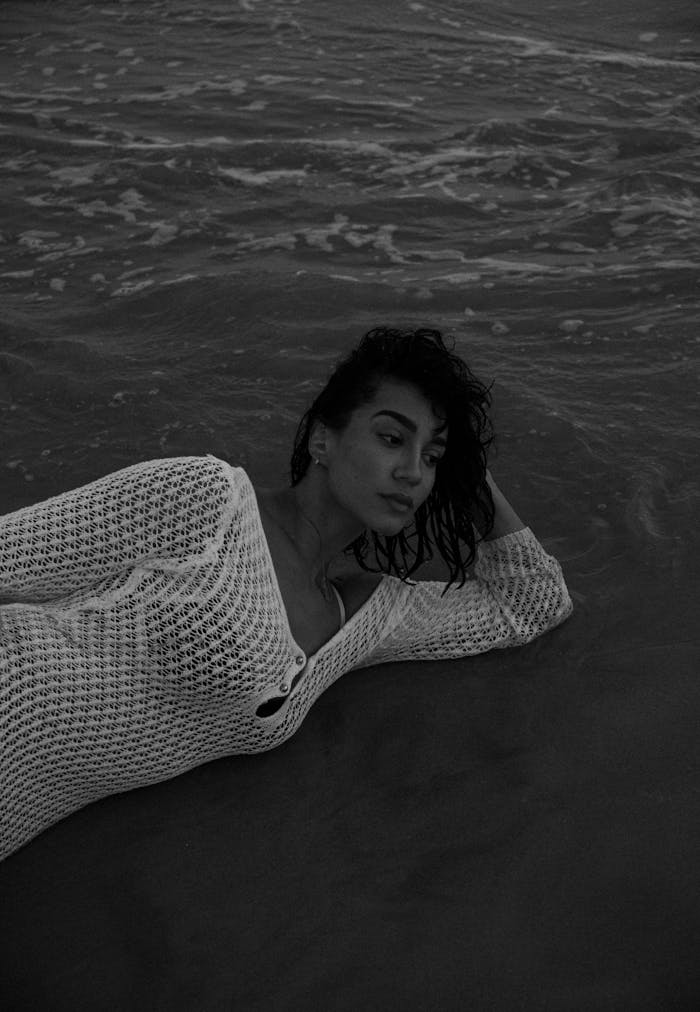 about-04 Artistic black and white portrait of a woman posing gracefully on the water's edge.